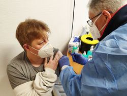 Zu sehen sind der Malteser Arzt Dr. Hans Josef Bastian beim Impfen einer Dame. Beide tragen eine FFP-2 Maske.